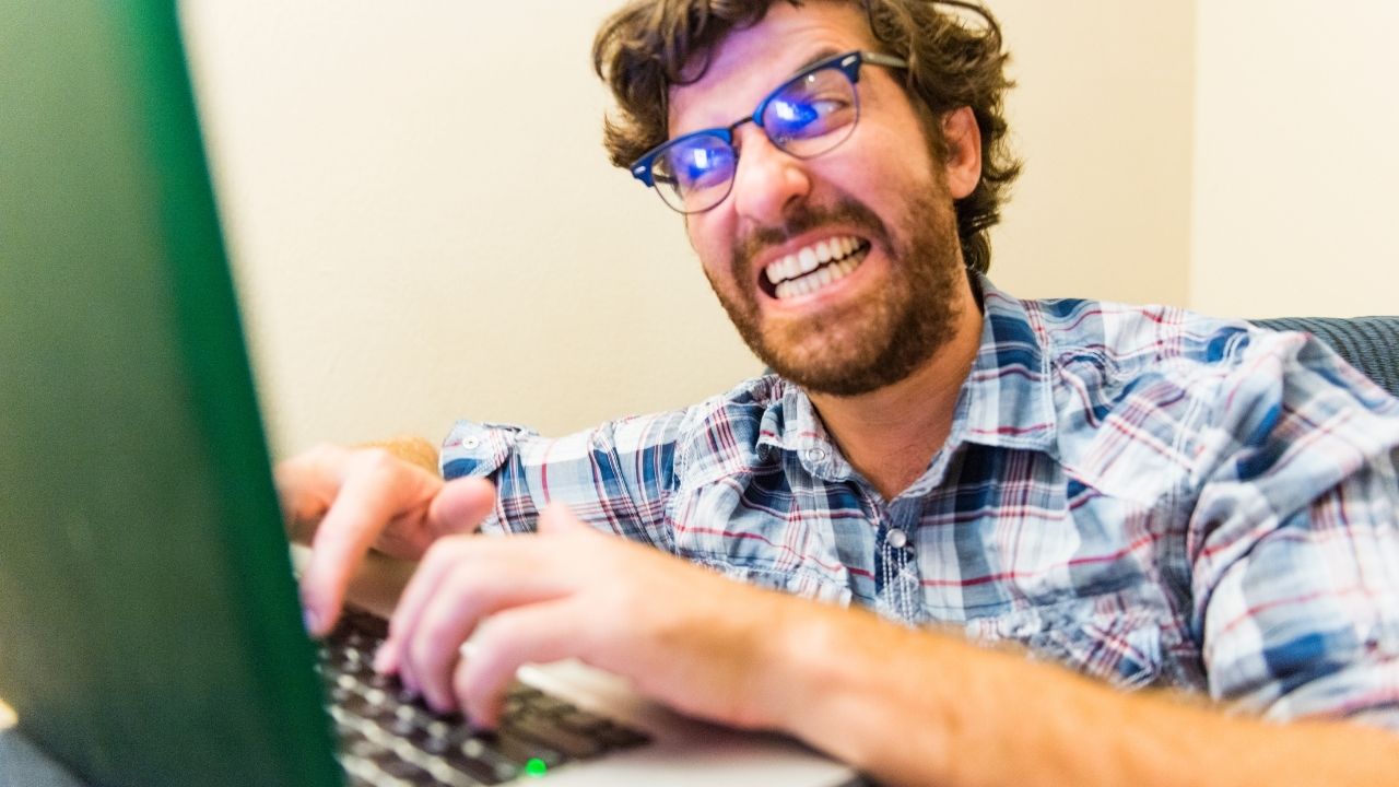 man typing furiously on laptop